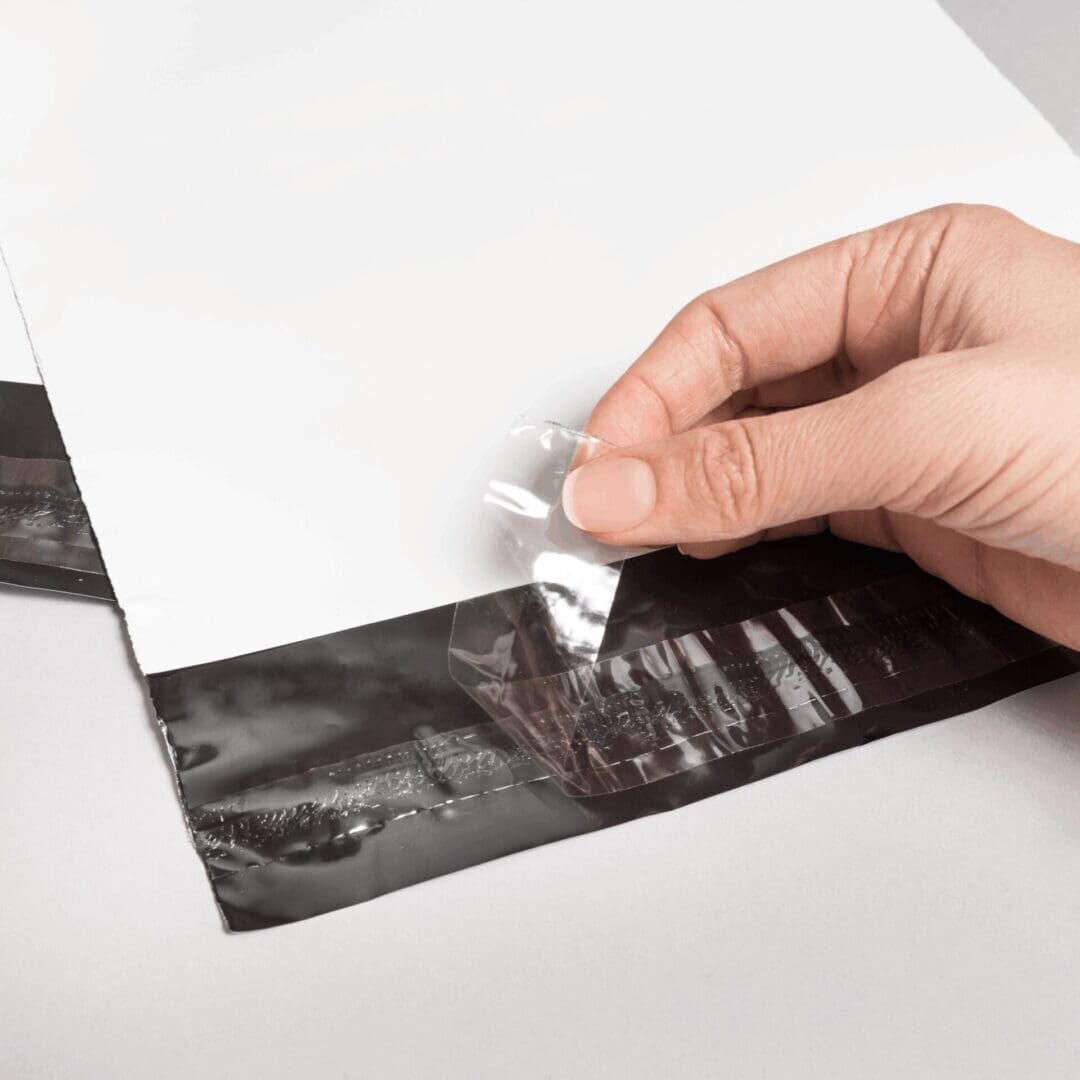 Hand peeling adhesive strip from envelope.
